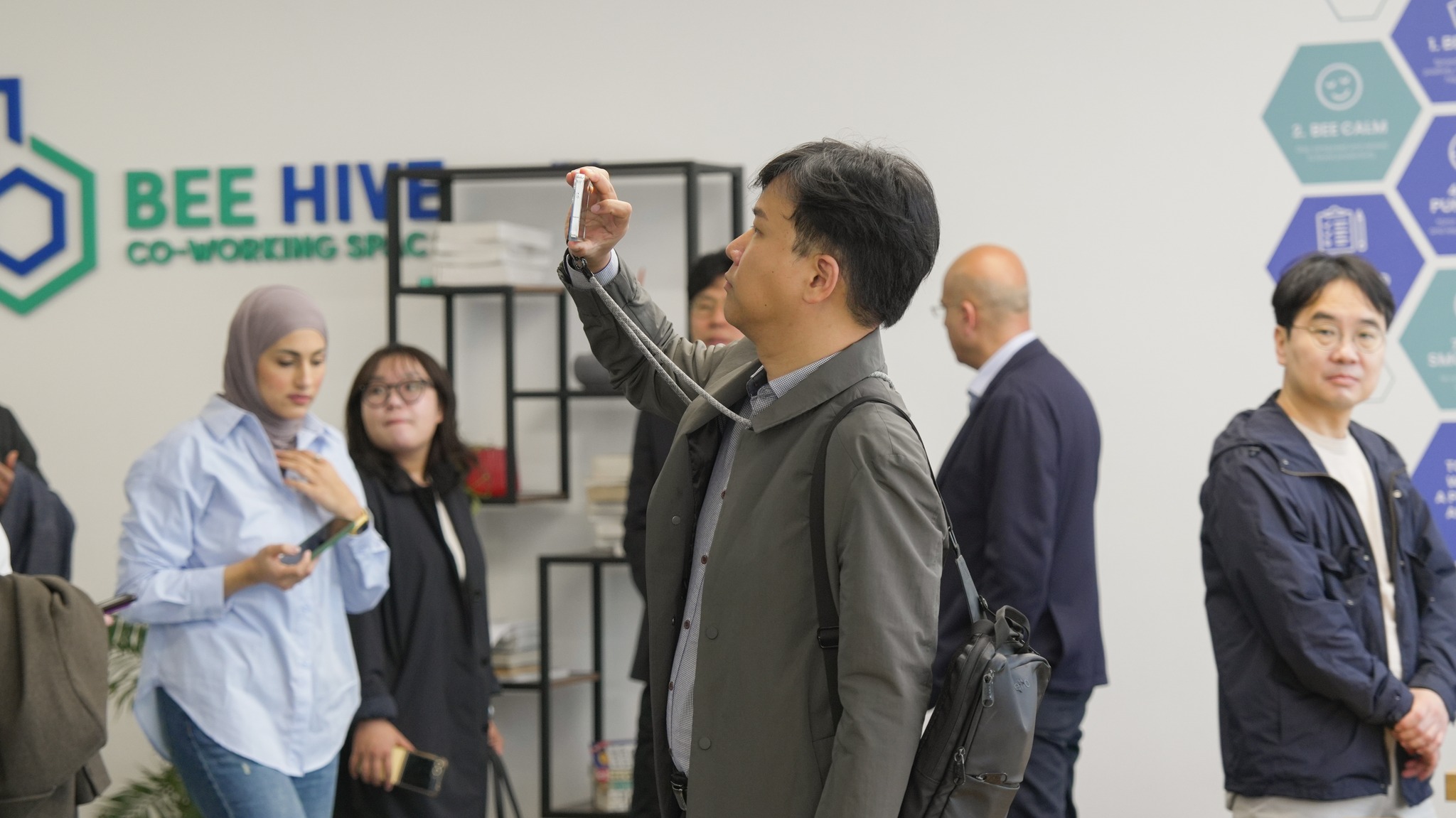 Visitors being shown around in front of the Bee Hive signage