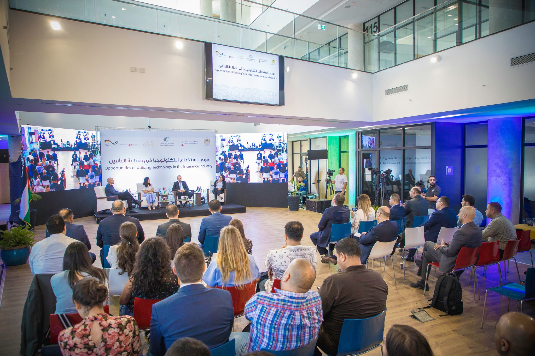 A large screen and a seated audience during a conference session